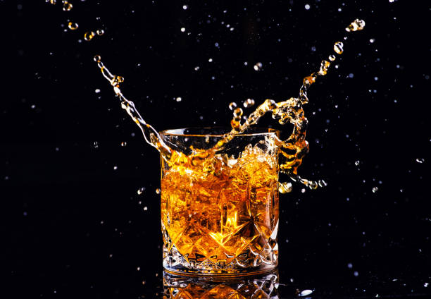 istock whiskey with splash on black background, brandy in a glass 1189230043