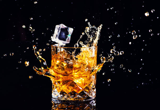 istock whiskey with splash on black background, brandy in a glass 1189230047