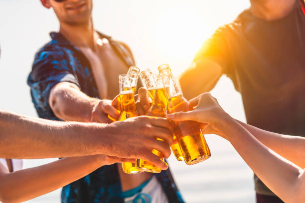 the hands holding bottles with beer and making cheers - sky human hand water white imagens e fotografias de stock