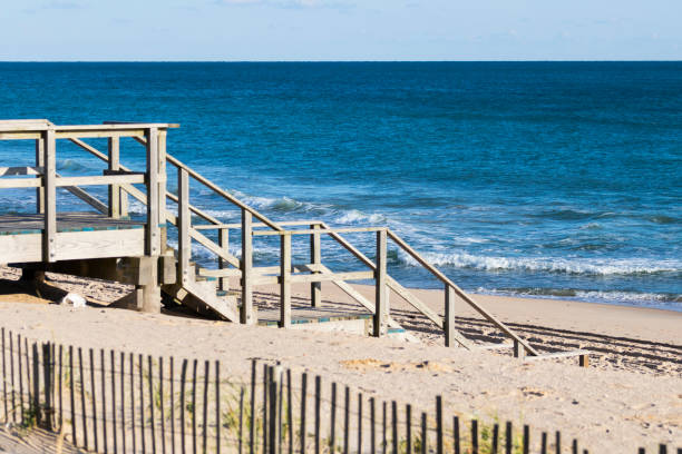 Wooden stairway leads to access of public/private beach, with dune protection fencing in foreground