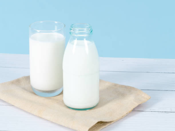 istock Milk bottles on table with blue background. 1189256704