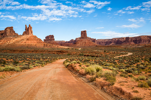 Red dirt road through towers of Southern Utah. Road trip taking the scenic route offroading.