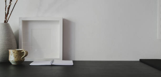 istock Close-up view of trendy workplace with copy space and mock up frame on black table and white wall 1189264915