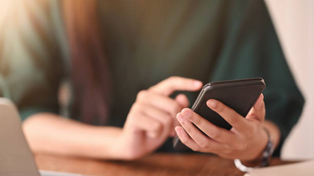 istock Close up shot female using her smartphone on wood table. 1189265618