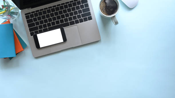 istock Office desk laptop, mockup smartphone with coffee on blue background. 1189265643