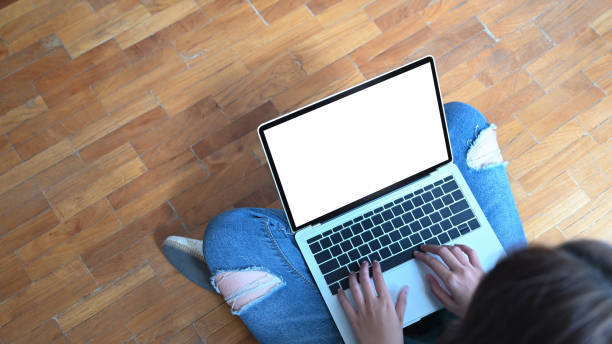 istock Woman sitting on floor and using mockup laptop computer with top view. 1189266132
