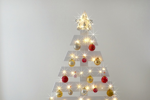Christmas home decor. Wooden white alternative christmas tree with red and gold balls background on beige wall background.New Year winter holidays.Festive shiny radiant background.