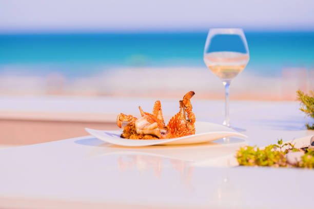 Delicious red crab cooked with yellow rice, served on a white plate on a white table with side and background out of focus. Concept of gastronomic seafood.