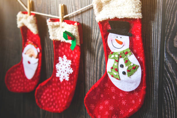 istock Three red stocking with fir-tree branches and christmas decorations on wooden table 1189274178