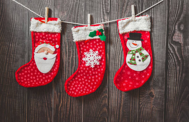 istock Three red stocking with fir-tree branches and christmas decorations on wooden table 1189274182