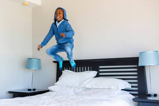 istock Excited Young Boy Jumping on the Bed 1189281120
