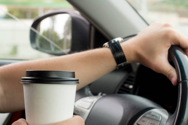 istock young man holding a paper coffee cup while driving 1189282825