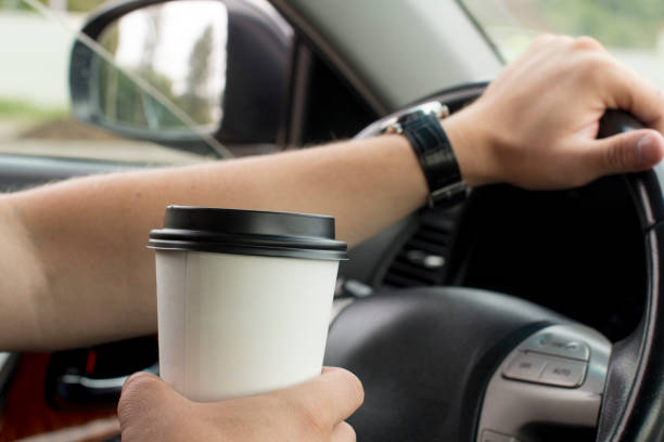 istock young man holding a paper coffee cup while driving 1189282831