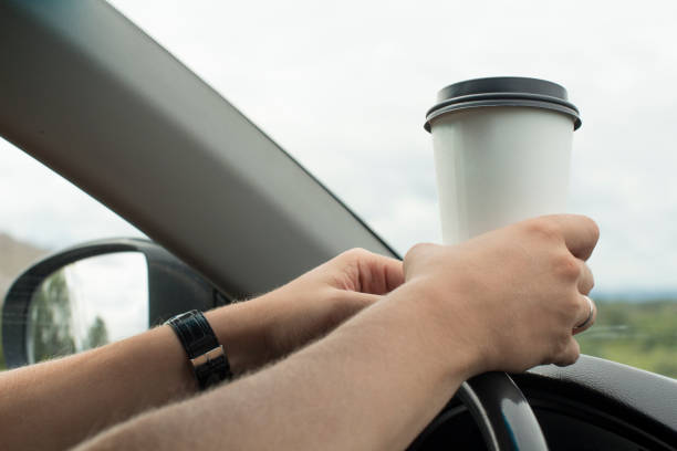 istock young man holding a paper coffee cup while driving 1189282835