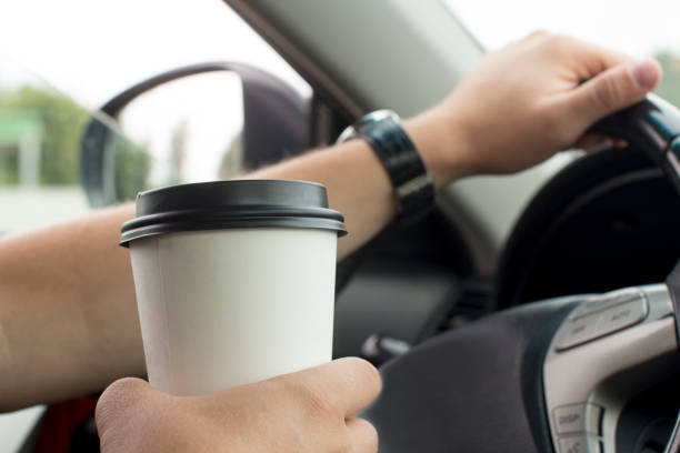 istock young man holding a paper coffee cup while driving 1189282837