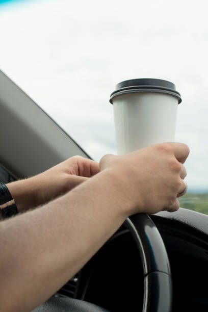 istock young man holding a paper coffee cup while driving 1189282846