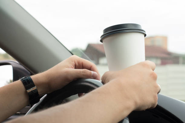 istock young man holding a paper coffee cup while driving 1189282847