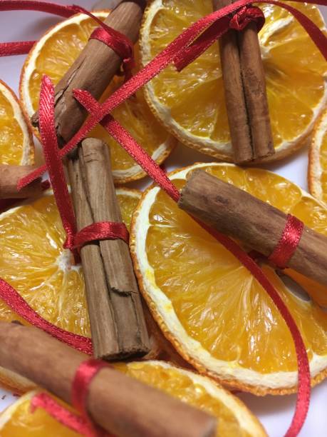 Decorazione natalizia, fette d'arancia con bastoncino di cannella legato con un filo rosso - foto stock