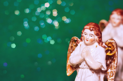 Porcelain angel on green bokeh background with copy space