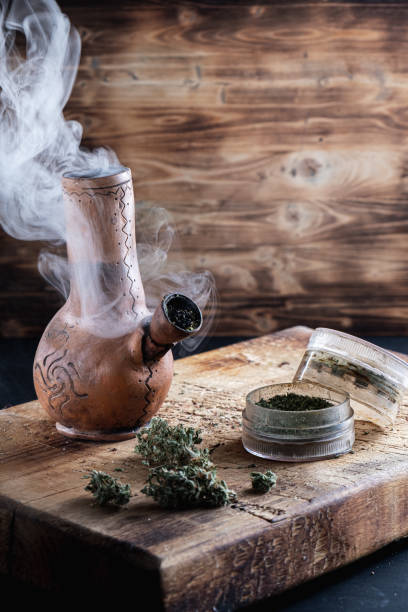 istock Old bong and open grinder cannabis and marijuana in smoke are located. Vertical composition 1189293440