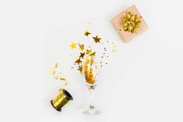 istock Champagne glass with gold glitter, gift box and space for text on white background, top view. Hilarious celebration 1189293972