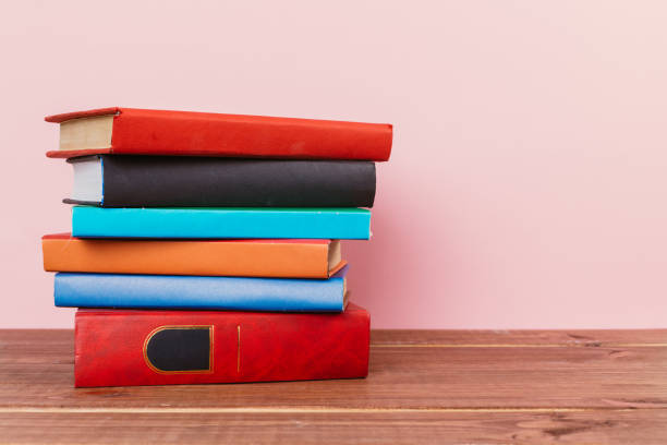 istock Simple Simple composition of many hardback books, unprocessed books on a wooden table and a pale pink background. back to school. Copy space Education. 1189294307
