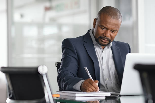 uomo d'affari maturo che scrive su documenti - working office businessman busy foto e immagini stock