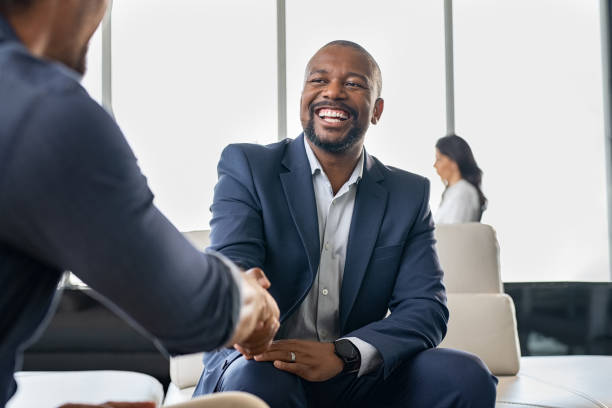Business people shaking hands Two happy mature business men shaking hands in modern office. Successful african american businessman in formal clothing closing deal with handshake. Multiethnic businessmen shaking hands during a meeting. black business stock pictures, royalty-free photos & images