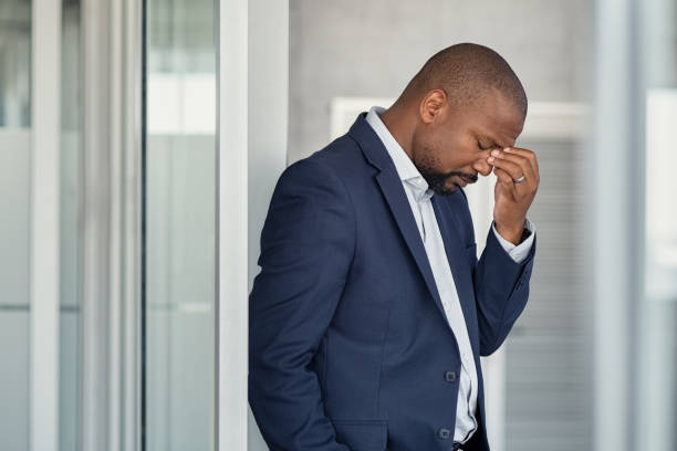 homme d'affaires stressé avec la position de mal de tête - tired men african descent sadness photos et images de collection