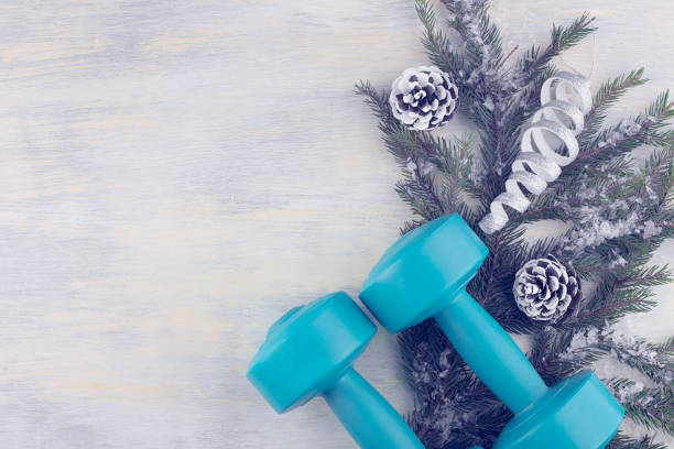 dumbbells en el fondo de una rama de abeto con decoraciones navideñas. - holiday healthy lifestyle weight christmas fotografías e imágenes de stock