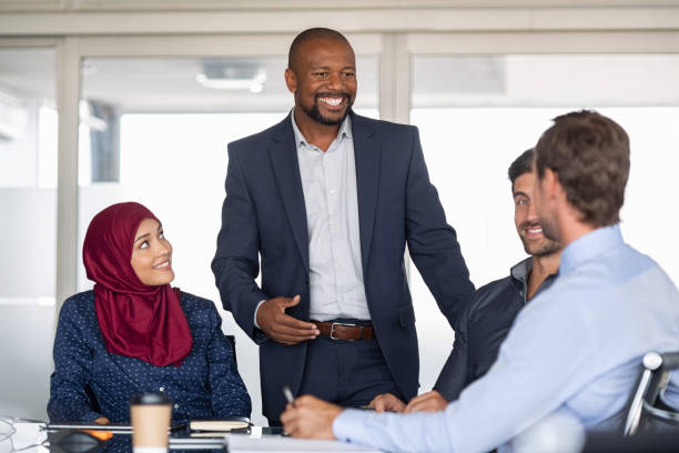 Multiethnic business people in meeting Entrepreneurs, partners and islamic woman conference in modern meeting room. Happy mature african businessman putting forward his suggestions to colleagues. Group of multiethnic business people brainstorming together. west asia stock pictures, royalty-free photos & images