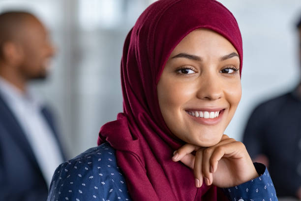 Islamic business woman in hijab smiling Portrait of young muslim woman wearing hijab in office while looking at camera. Close up face of arabic business woman covered with headscarf smiling. Successful arab businesswoman in modern office. hijab photos stock pictures, royalty-free photos & images