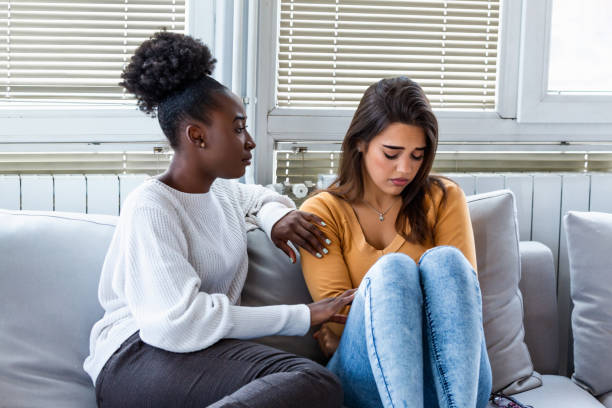 Sad girl and supporting friends trying to solve a problem. Two sad diverse women talking at home. Female friends supporting each other. Problems, friendship and care concept Sad girl and supporting friends trying to solve a problem. Two sad diverse women talking at home. Female friends supporting each other. Problems, friendship and care concept friendship support stock pictures, royalty-free photos & images