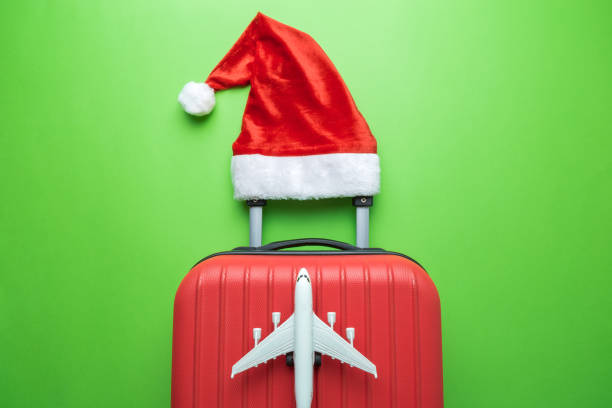 istock Suitcase with Santa hat and airplane model on green background minimal creative Christmas holiday travel concept. 1189305391