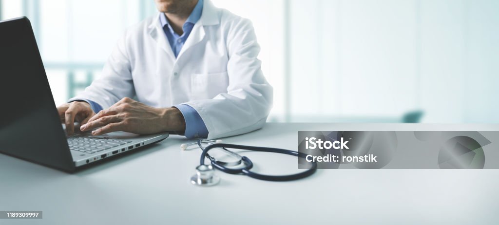 Online-Ärztliche Beratung - Arzt arbeitet auf Laptop-Computer in Klinik-Büro. Kopierraum - Lizenzfrei Arzt Stock-Foto