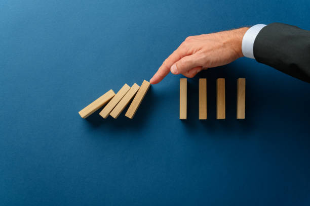 istock Collapsing dominos being stopped my a crisis business manager 1189313539