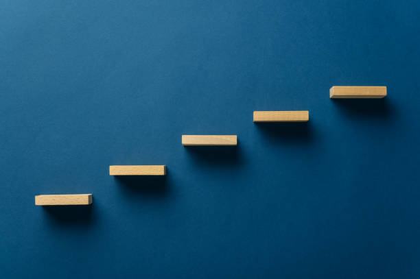 Wooden pegs forming a stairway Wooden pegs place over navy blue background in a stairway like structure in a conceptual image. With copy space. ladder photos stock pictures, royalty-free photos & images