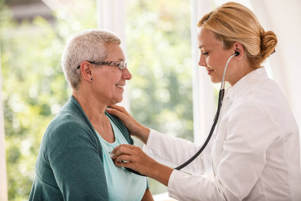 Doctor listening patient's heartbeat stock photo