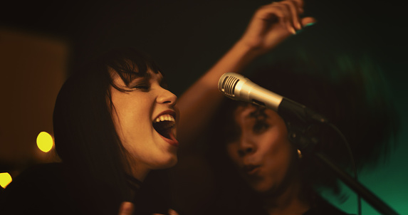 Shot of two young women singing on stage in a club