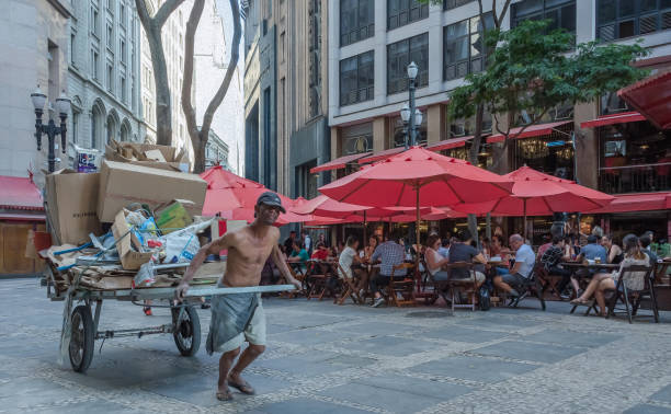Man pulling a cart in downtown Sao Paulo Sao Paulo city, Sao Paulo state, Brazil - October 05, 2019:Man pulling a recyclable trash wagon in front of a fancy restaurant in Sao Paulo. horse cart photos stock pictures, royalty-free photos & images