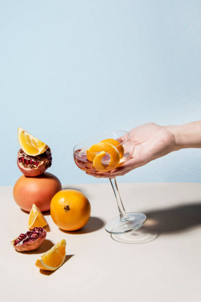 Woman's hand with summer cocktail and a fruit tower from orange, pomegranate and lemon slice besides. stock photo