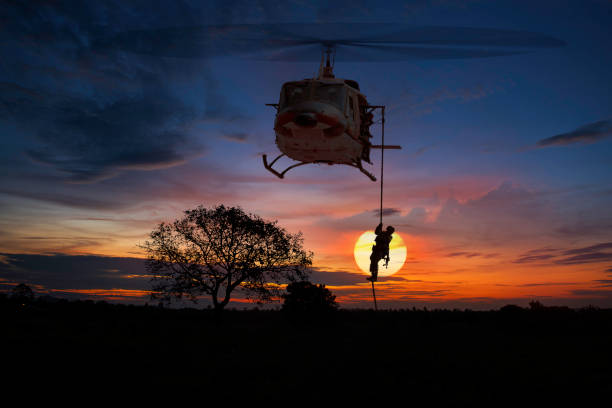 istock A Silhouette helicopter soldier under army training and big tree at sunset twilight sky background with black cloudy. 1189323102