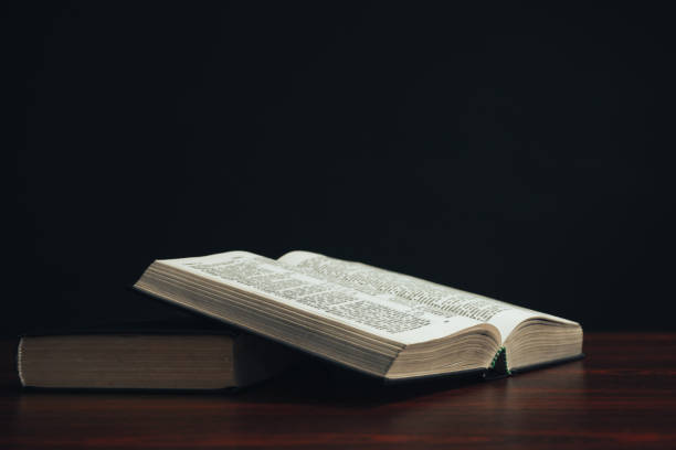 istock Open bible on a  red wooden table. Beautiful black background. 1189324457