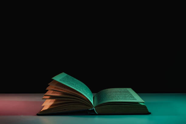 istock Beautiful open book in the color light on a table and night background. 1189325604