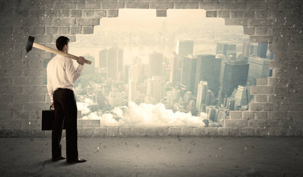 istock Business man hitting wall with hammer on city view 1189326686