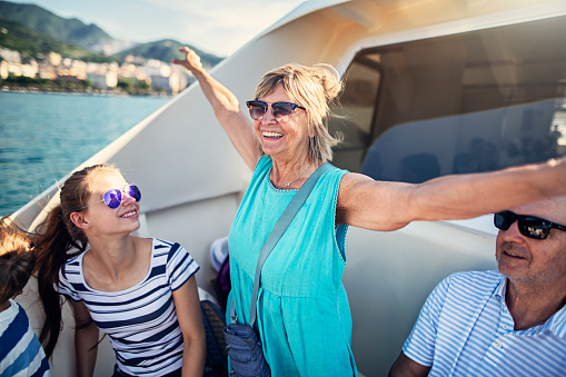 Senior woman with family travelling by boat near Amalfi coast, Italy