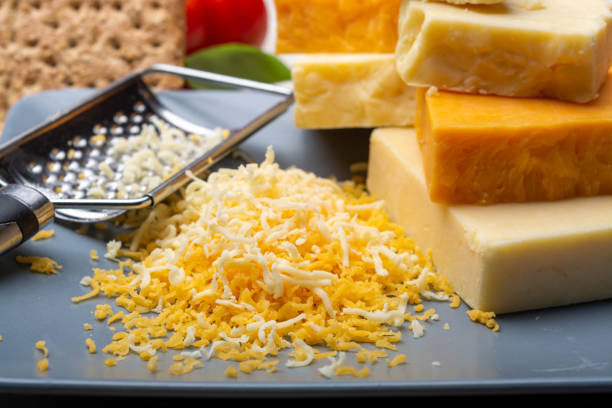 istock Cheese collection, matured and orange original British cheddar cheese in blocks and grated served on grey plate 1189329319