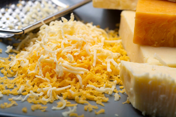 istock Cheese collection, matured and orange original British cheddar cheese in blocks and grated served on grey plate 1189329345