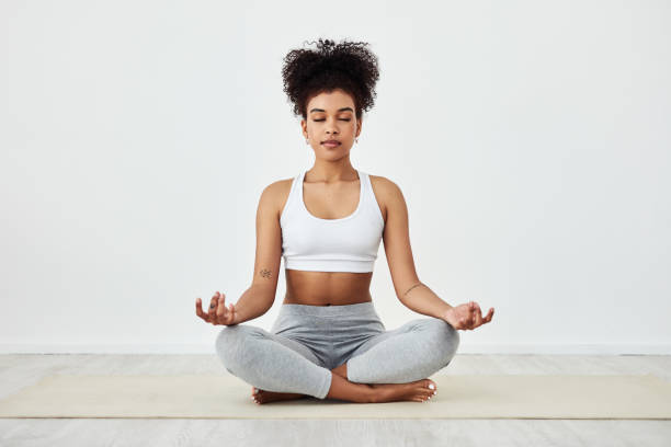 Be mindful of how awesome you are Shot of a fit young woman meditating at home lotus position stock pictures, royalty-free photos & images