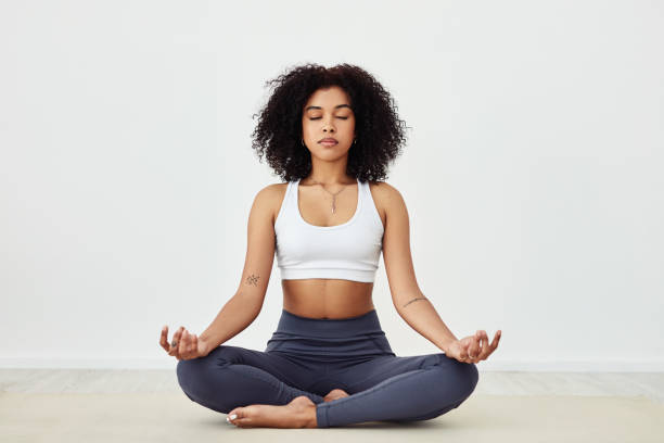 Listen to the rhythm of your body Shot of a fit young woman meditating at home yoga lotus position meditating women stock pictures, royalty-free photos & images